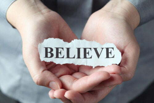 35232049 - torn piece of paper with the word "believe" in the woman's palms.